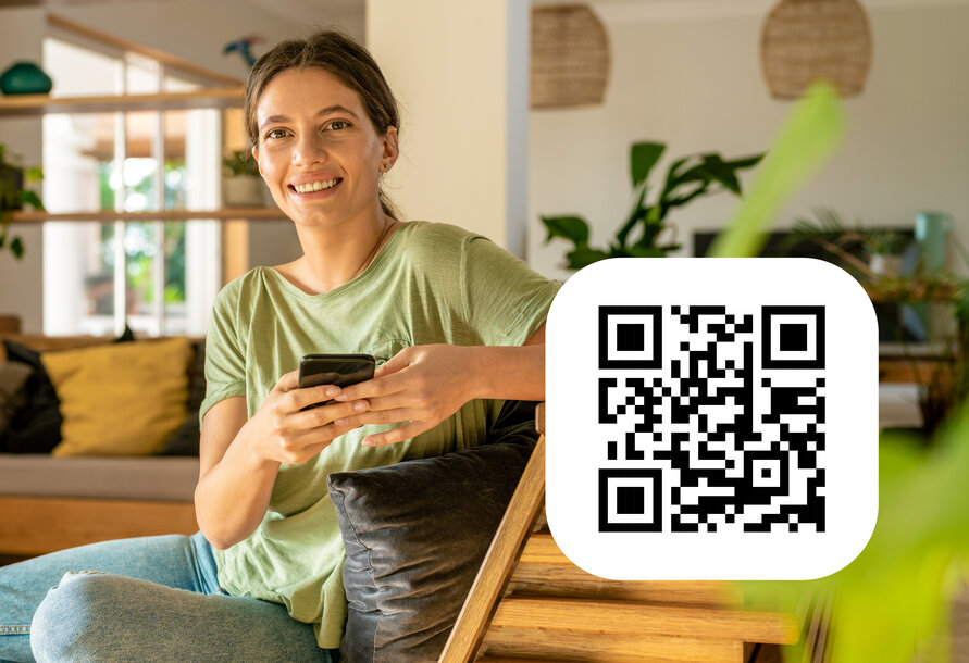 Lächelnde Frau mit Smartphone und QR-Code zum Download der MONTANA Service-App