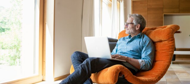 Entspannter Mann sitzt mit Laptop im Sessel – Kontaktmöglichkeiten und Service-Team von MONTANA