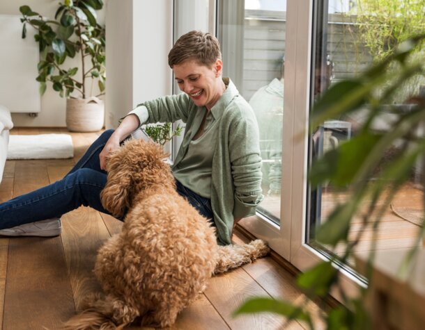Eine lächelnde Frau mit ihrem Hund in einem gemütlich beheizten Wohnraum – Symbolbild für die Effizienz und Behaglichkeit durch schwefelarmes Heizöl