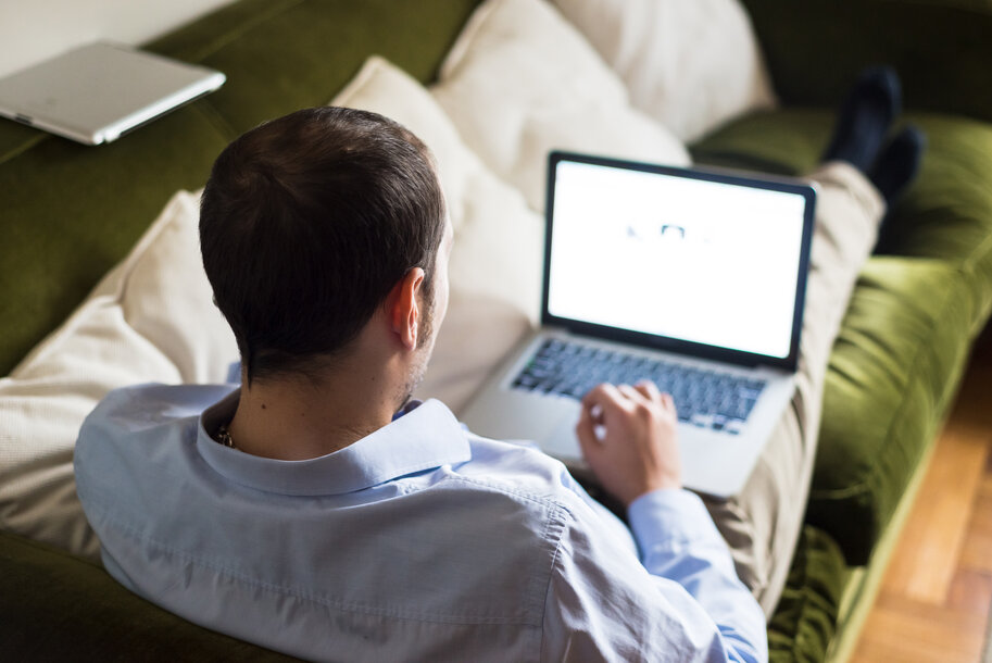 Mann sitzt bequem auf dem Sofa und nutzt das MONTANA Kundenportal auf seinem Laptop