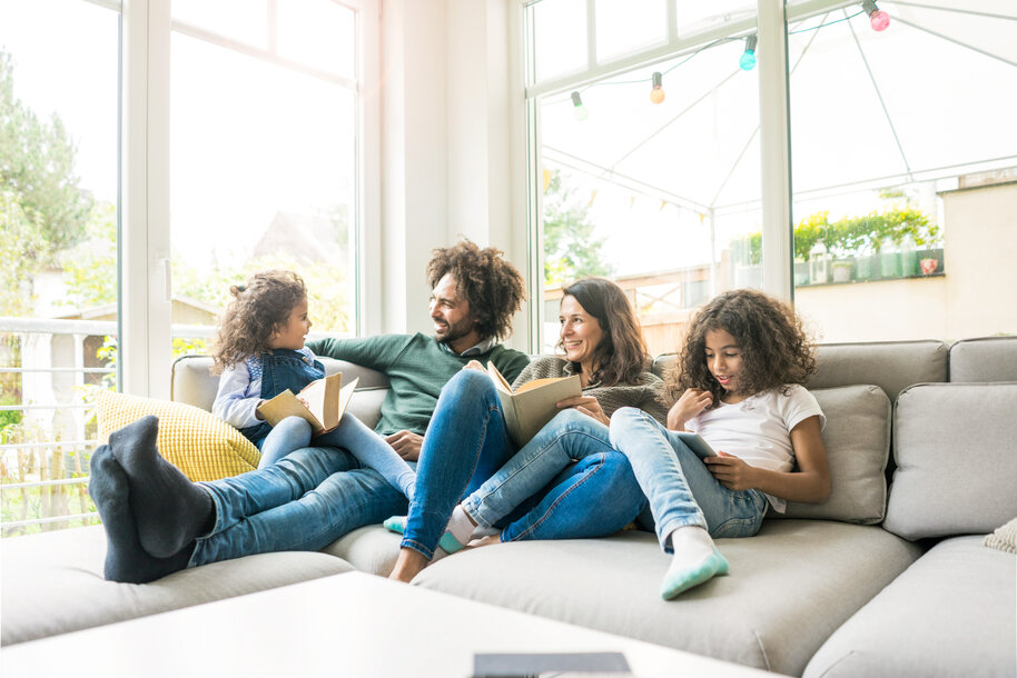 Vierköpfige Familie entspannt im Wohnzimmer – Symbolbild für den Gasverbrauch je nach Haushaltsgröße