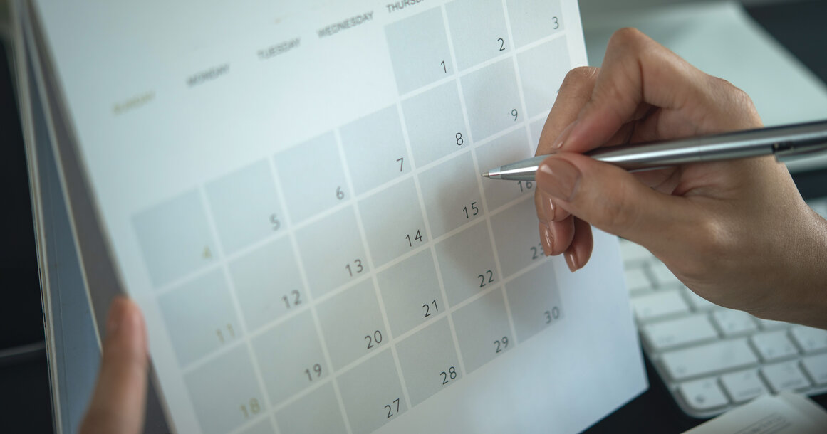 Hand mit Stift über einem Kalender – Planung von Wechseltermin und Kündigungsfrist