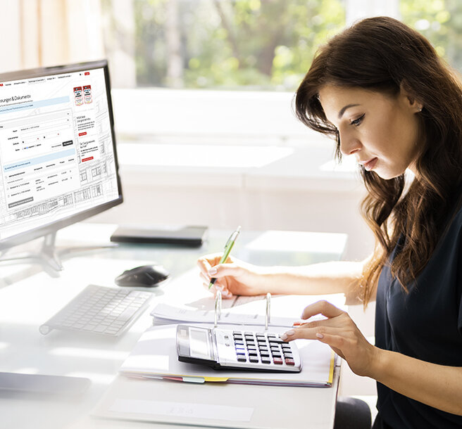 Frau arbeitet am Schreibtisch mit Taschenrechner, auf dem Monitor ist das MONTANA Kundenportal geöffnet – Digitale Verwaltung von papierlosen Rechnungen