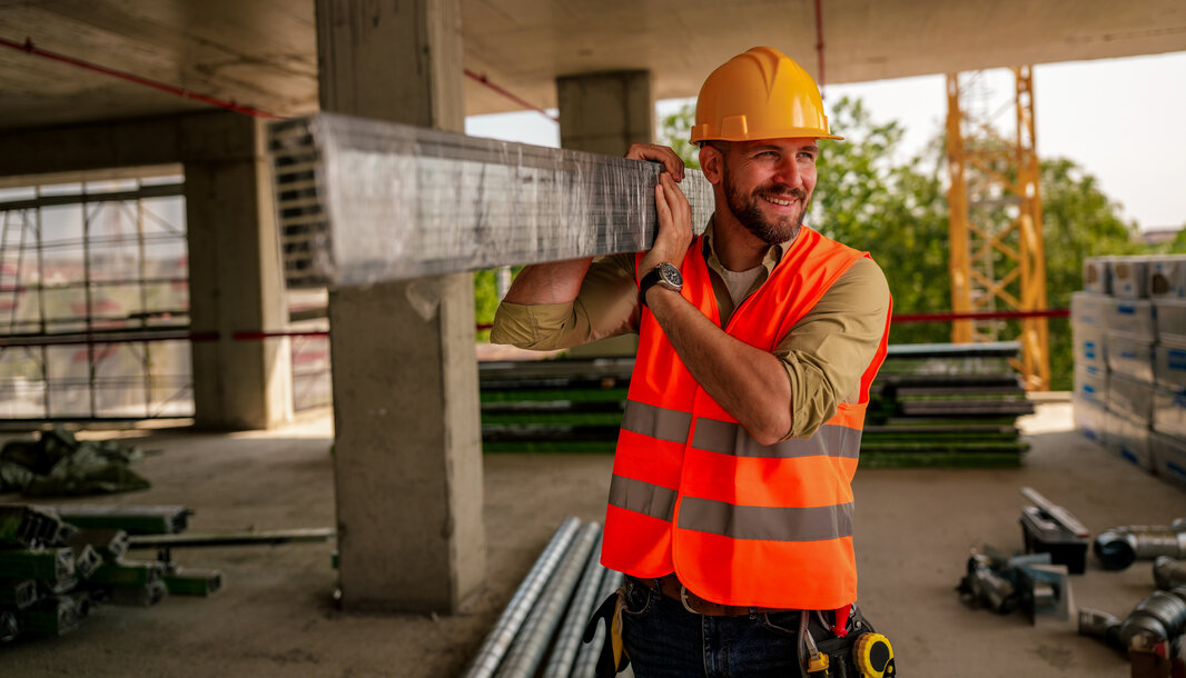 Ein lächelnder Bauarbeiter mit Helm und Warnweste auf einer Baustelle – Symbolbild für die gute Qualität und Verlässlichkeit von MONTANA Heizöl Extra Leicht