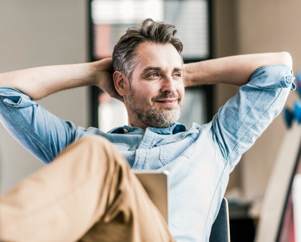 Ein lächelnder Key Account Manager lehnt sich entspannt im Büro zurück – Erstellung maßgeschneiderter Energie-Angebote für Ihre Liegenschaften durch MONTANA