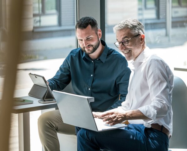Zwei Männer besprechen entspannt Daten an einem Laptop – Kostenlose Energieberatung durch MONTANA zur Senkung von Heizkosten