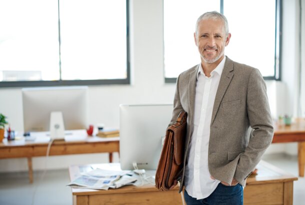 Lächelnder Mann mit Aktentasche im Büro – Newsletter-Anmeldung für die Immobilienwirtschaft