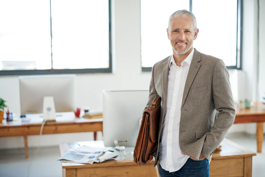 Lächelnder Mann mit Aktentasche im Büro – Newsletter-Anmeldung für die Immobilienwirtschaft