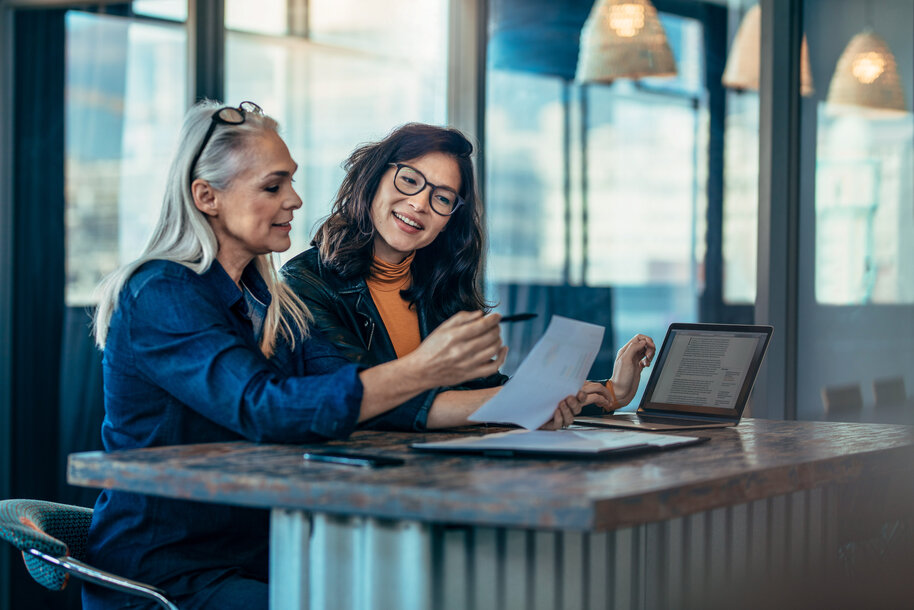 Zwei Frauen besprechen ein Dokument am Schreibtisch – Ratgeber zur Versteuerung der THG-Prämie für Geschäftskunden