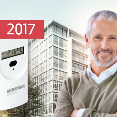 Ein lächelnder Mann vor einem modernen Gebäude neben einem MONTANA Messgerät – Meilenstein 2017: Gründung der MONTANA Energy Services zur Verbrauchserfassung