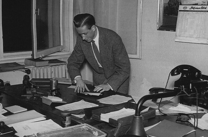 Historisches Schwarz-Weiß-Foto von Karl Koburger bei der Arbeit am Schreibtisch – Ausdruck der über 65-jährigen Energie-Erfahrung und Expertise von MONTANA