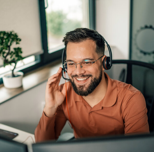 Ein freundlich lachender MONTANA Kundenberater mit Brille und Headset im Gespräch – Kompetente Hilfe bei all Ihren Energie-Anliegen