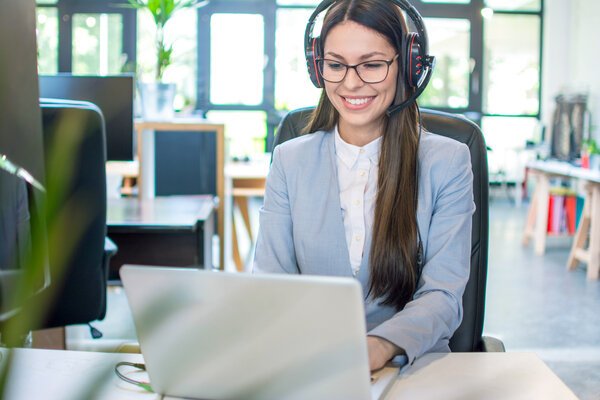 Eine lächelnde MONTANA Kundenberaterin mit Brille und Headset am Laptop – Ihr digitaler Service für alle Fragen zu Strom und Gas