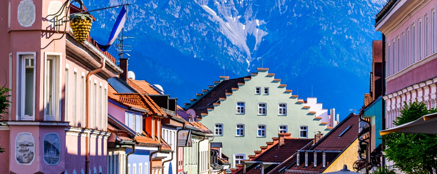 Bunte historische Häuserfassaden mit Alpenpanorama im Hintergrund – MONTANA Heizöl Lieferung in Murnau und Penzberg