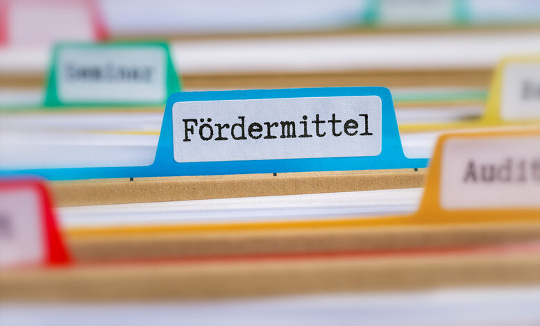 Nahaufnahme eines blauen Aktenreiters mit der Aufschrift 'Fördermittel' – Ratgeber zu finanziellen Zuschüssen im Gebäudeenergiegesetz (GEG)