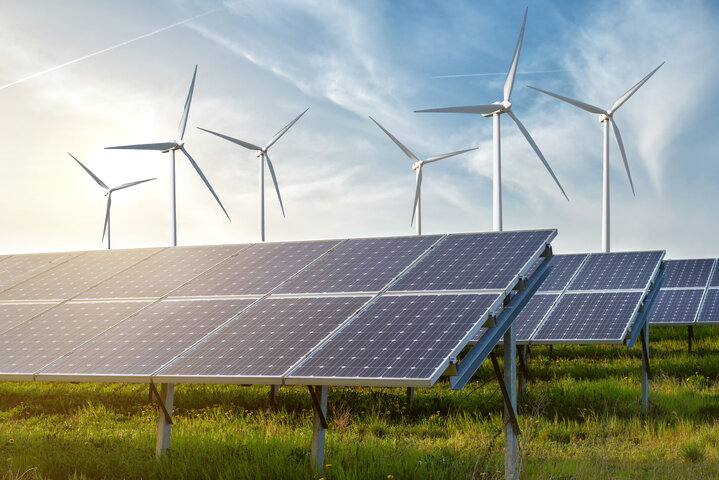 Solarmodule und Windkraftanlagen auf einer grünen Wiese