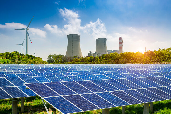 Photovoltaikanlagen, Windräder und Kraftwerkstürme bei Sonnenaufgang – Symbolbild zur Zusammensetzung der Stromerzeugung in Deutschland