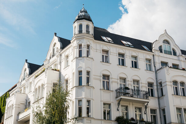 Weiße Fassade eines klassischen Altbau-Mehrfamilienhauses – Ratgeber für Hausverwalter zum GEG und Gas-Etagenheizungen