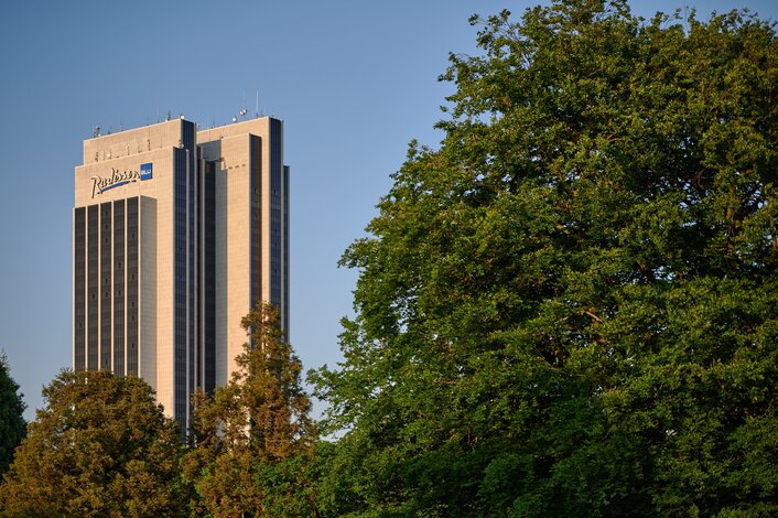 Das Radisson BLU Hotel Hamburg hinter herbstlich gefärbten Bäumen im Park – Veranstaltungsort des Miet-Verwalterforums für die Immobilienwirtschaft