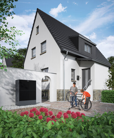 Eine moderne Wärmepumpe an der Außenwand eines Wohnhauses, im Hintergrund reparieren zwei Kinder ein Fahrrad – MONTANA Wärmepumpen-Lösungen für Bestandsgebäude