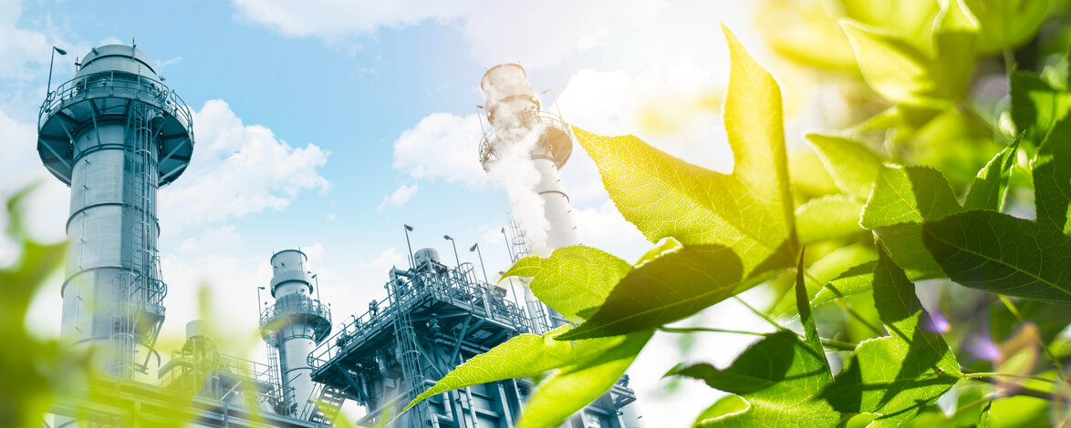 Gegenüberstellung einer Industrieanlage und leuchtend grünen Blättern – Umweltfreundliche Schmierstoffe und Reraffinate zur CO2-Reduzierung