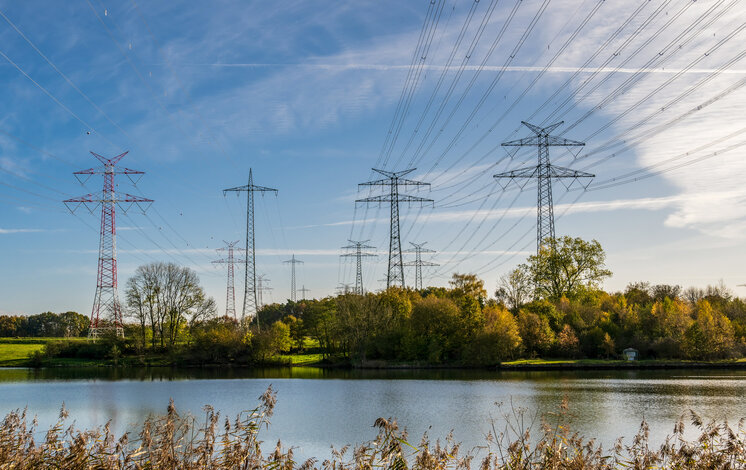 Hochspannungsleitungen über einem Fluss – Strom Standard basierend auf dem allgemeinen Strommix in Deutschland
