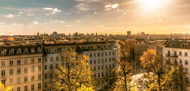 Panoramablick über eine Stadt mit vielen Wohnhäusern im warmen Sonnenlicht – Maßgeschneiderte Lösungen für Erdgas und Ökostrom für die Immobilienwirtschaft