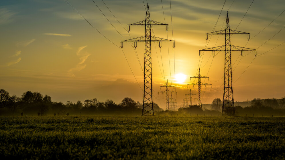 Hochspannungsmasten und Stromleitungen bei Sonnenuntergang – MONTANA Gewerbestromtarife für Unternehmen und Selbstständige