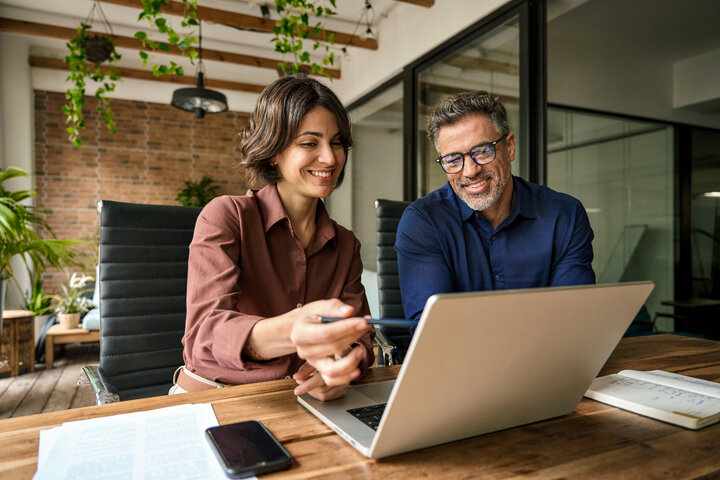 Zwei Geschäftspartner besprechen Energieverträge am Laptop – Stromtarife und digitale Services für die Immobilienwirtschaft