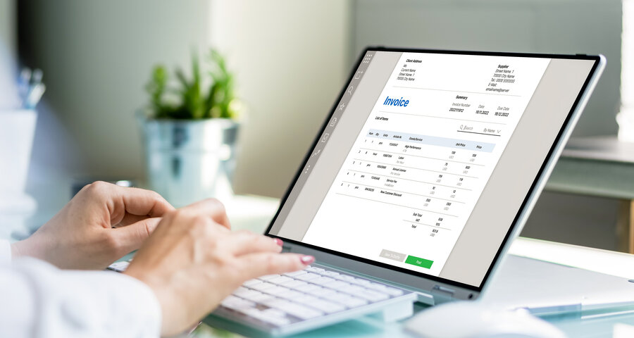 "Hände beim Tippen auf einer Tastatur vor einem Laptop mit digitaler Rechnung – Symbolbild für die digitale Hausverwaltung und automatisierte Prozesse bei MONTANA