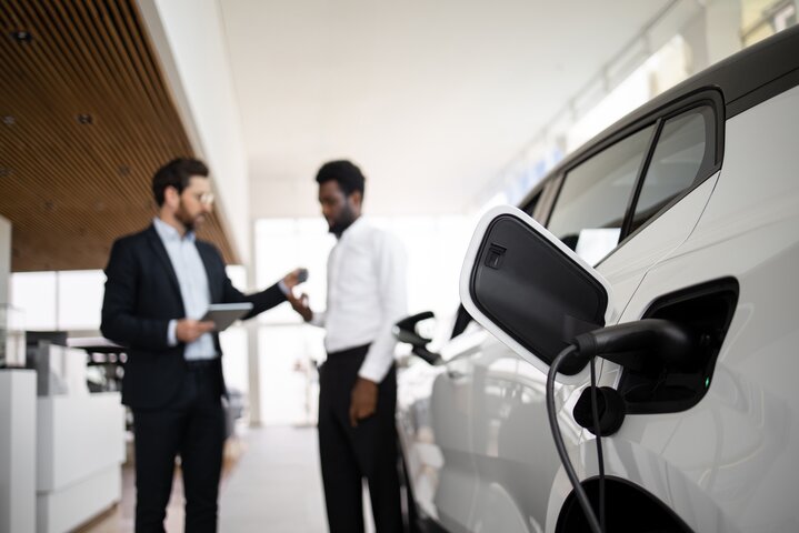 Übergabe eines ladenden Elektro-Firmenwagens mit Autoschlüssel im Autohaus.