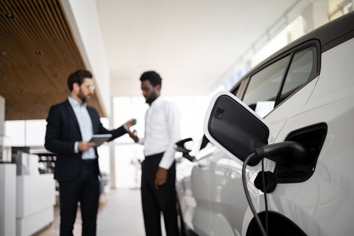 Übergabe eines ladenden Elektro-Firmenwagens mit Autoschlüssel im Autohaus.