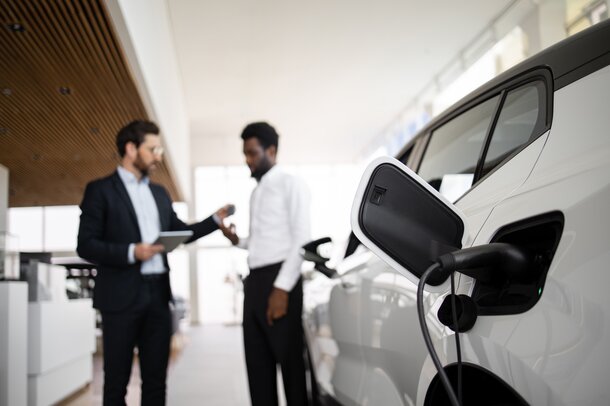 Übergabe eines ladenden Elektro-Firmenwagens mit Autoschlüssel im Autohaus.