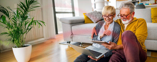 Ein lächelndes älteres Ehepaar schaut gemeinsam auf ein Tablet im Wohnzimmer – Symbolbild für den Vergleich attraktiver Erdgastarife von MONTANA