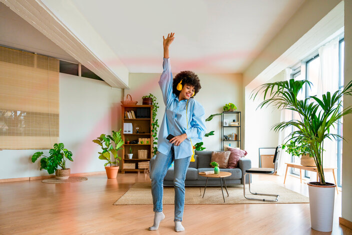 Frau tanzt mit Kopfhörern entspannt im Wohnzimmer – flexibler MONTANA Tarif Erdgas Vario