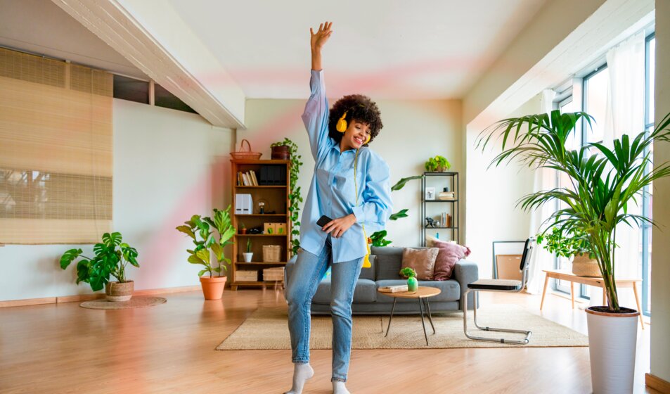 Frau tanzt mit Kopfhörern entspannt im Wohnzimmer – flexibler MONTANA Tarif Erdgas Vario