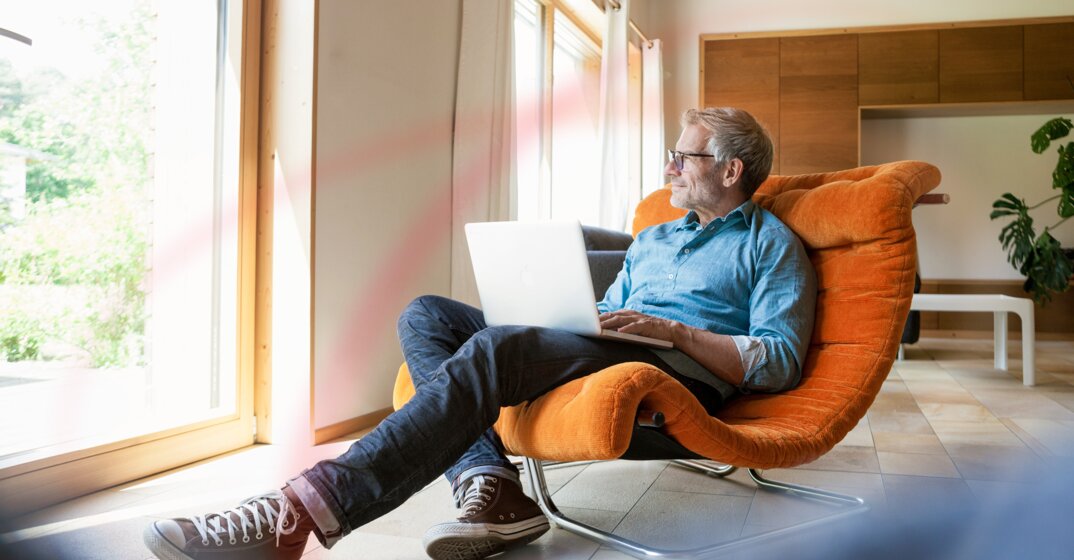 Entspannter Mann sitzt mit Laptop im Sessel – Heizölpreis-Rechner von MONTANA
