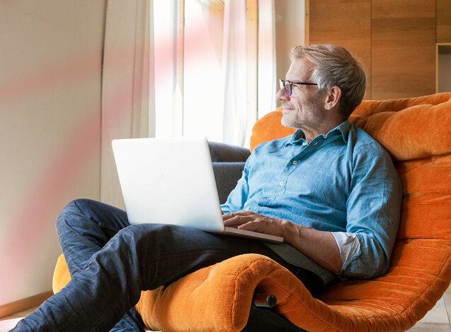 Entspannter Mann sitzt mit Laptop im Sessel – Heizölpreis-Rechner von MONTANA