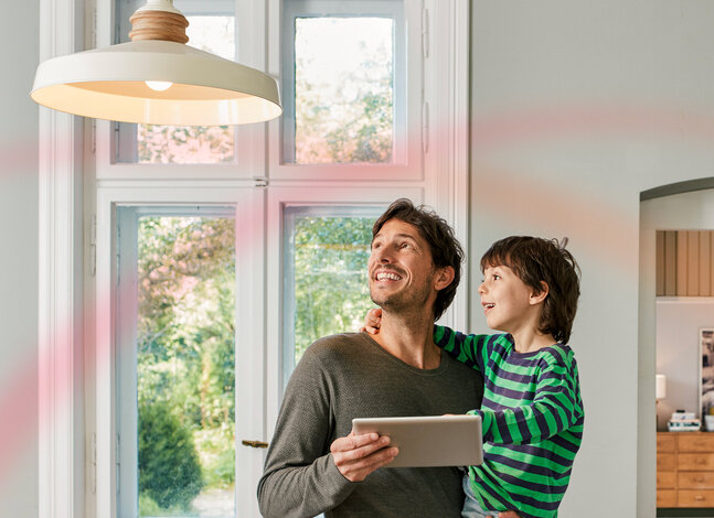 Ein Vater und sein Sohn blicken lächelnd aus dem Fenster – Symbolbild für den einfachen und schnellen Wechsel zu MONTANA Ökostrom