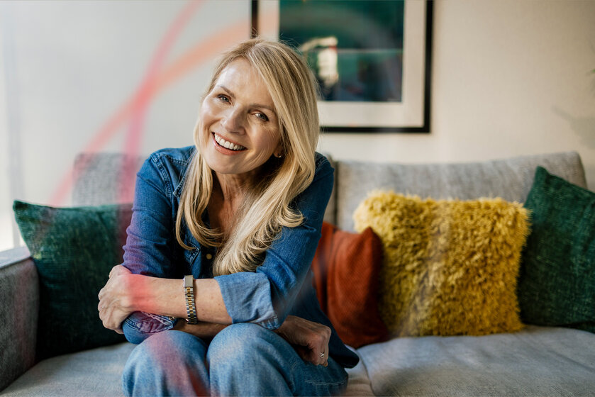 Lächelnde Frau auf Sofa genießt die Wärme – Angebote für günstiges MONTANA Heizöl