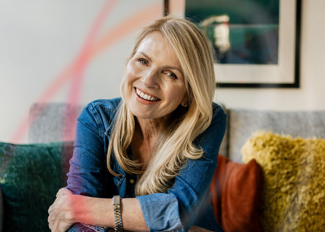 Lächelnde Frau auf Sofa genießt die Wärme – Angebote für günstiges MONTANA Heizöl