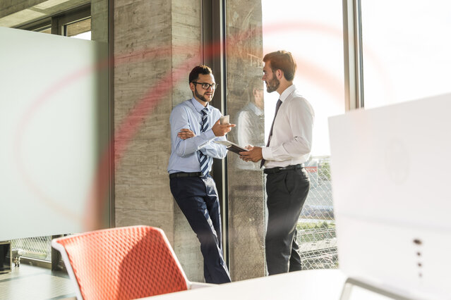 Zwei Männer besprechen stehend im Büro – Ratgeber zu Erdgastarifen für Geschäftskunden